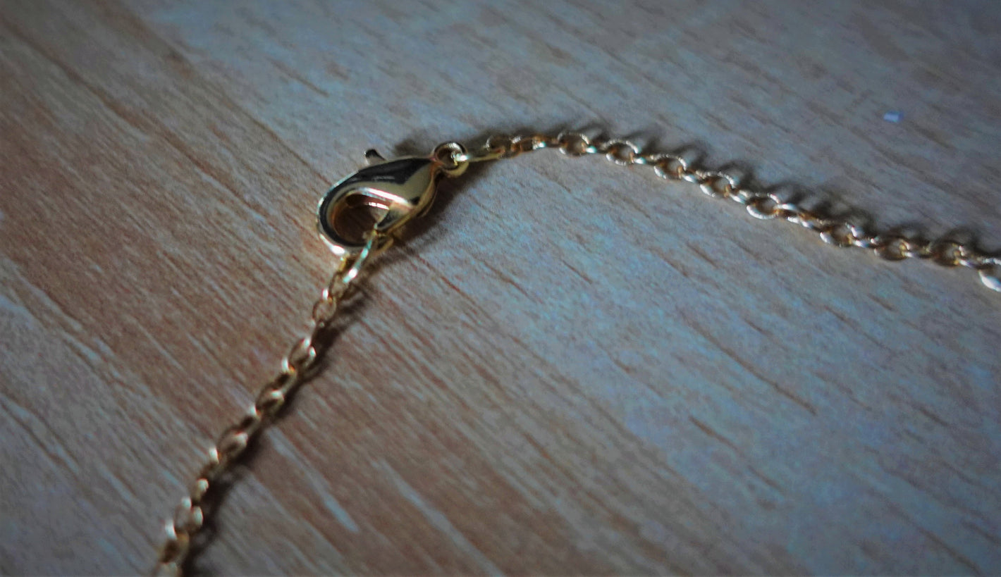 gold plated necklace chain laying on light colored wood 