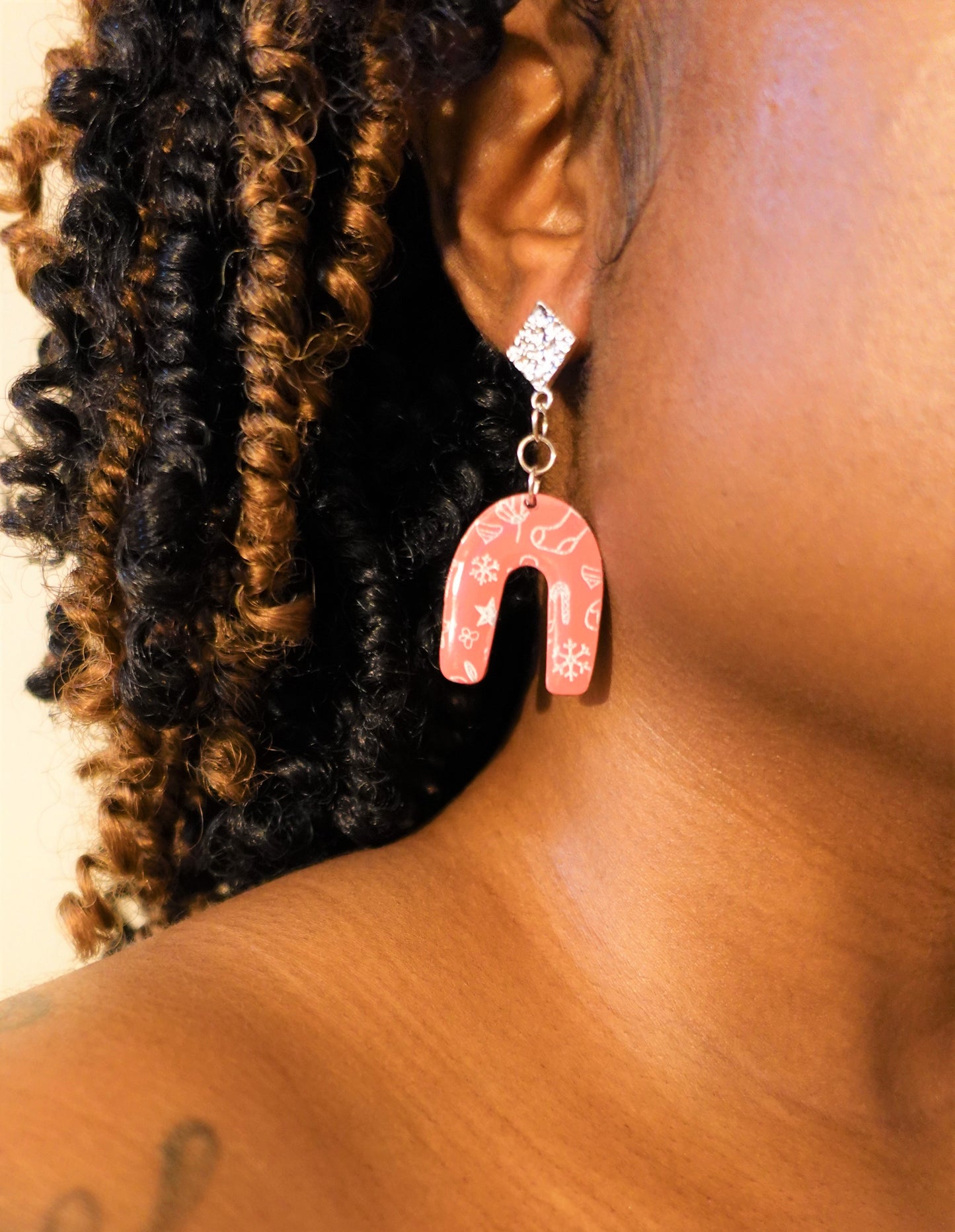 woman wearing red arched earrings with silver components and silver stenciled pattern